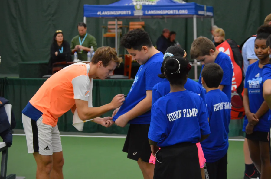 A Capital City Tennis Classic player signing shirts for young tennis fans